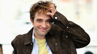 Robert Pattinson lächelt mit zerzausten Haaren