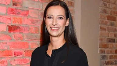 Pinar Atalay steht vor einer Steinwand und lächelt