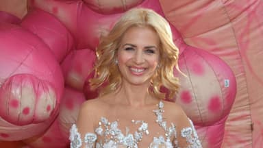 Susan Sideropoulos im weißen Glamour-Kleid, pinker Hintergrund