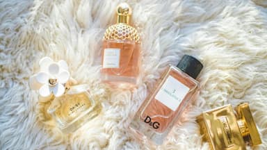 Verschiedene Parfums auf einem flauschigen weißen Teppich.