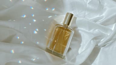 Parfum Flakon liegt auf einem Bettlaken mit Licht und Schatten