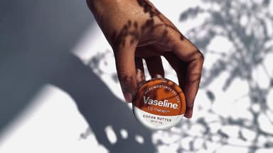 Frau hält eine kleine Dose mit Vaseline in der Hand.