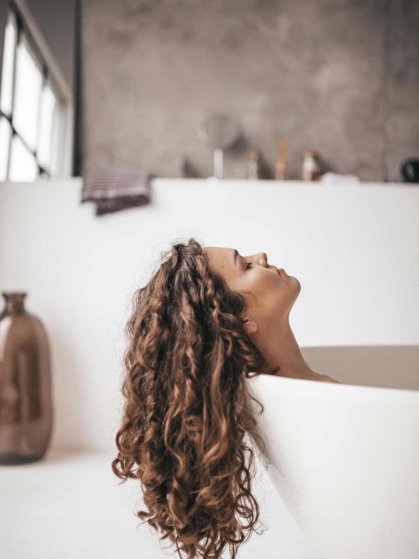Dicke Haare: Frau liegt in Wanne mit braunen Locken