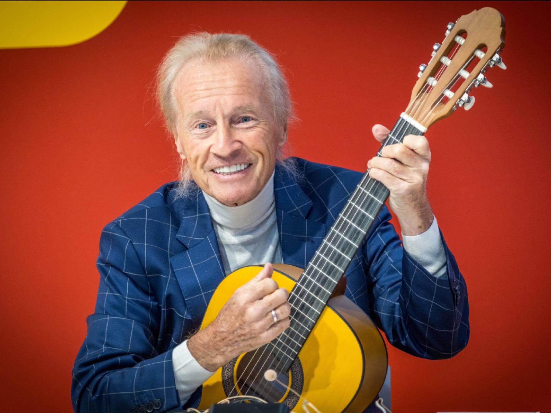 Christian Anders lächelt vor roter wand