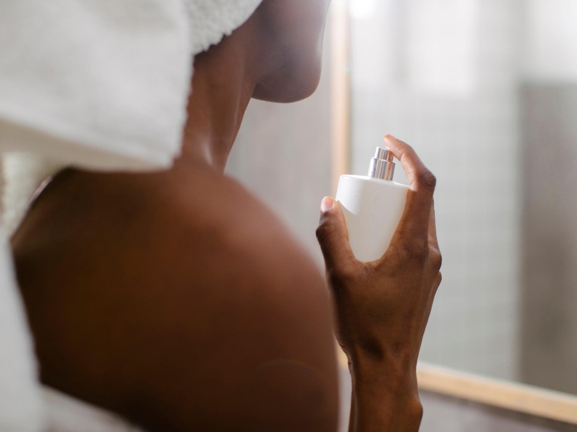 Manche Parfums haben eine besonders beruhigende Wirkung Frau sprüht nach dem Duschen Parfum auf.