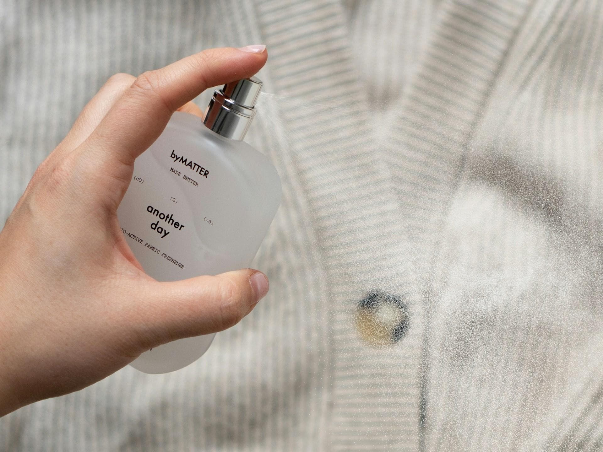 Frische Wäsche Parfum duftet sauber und rein. Jemand sprüht ein Parfum auf eine Strickjacke.