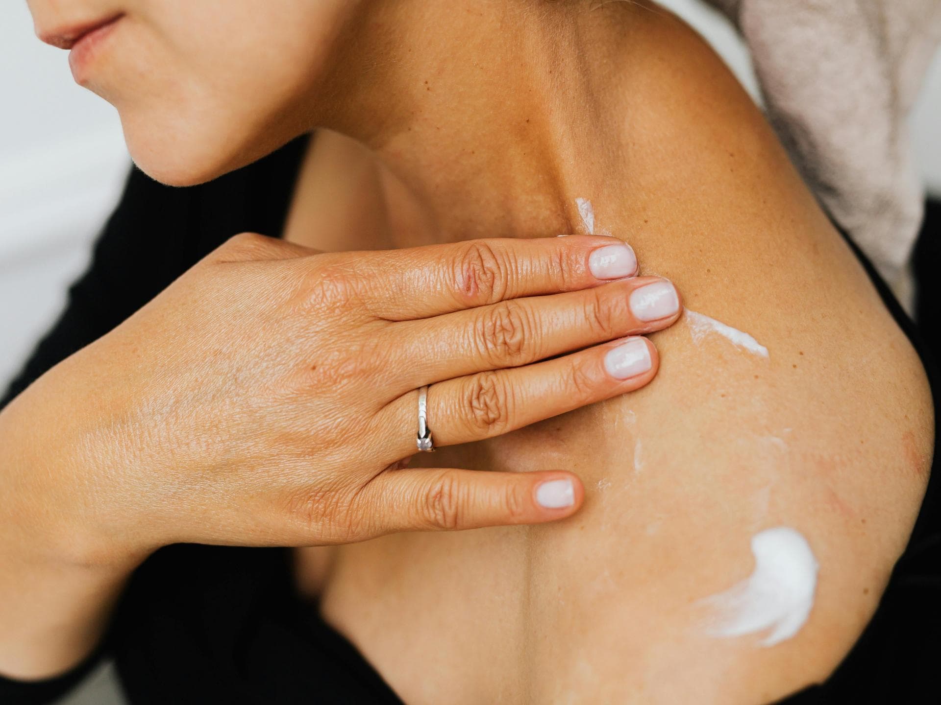 Frau cremt sich mit Bodylotion ein