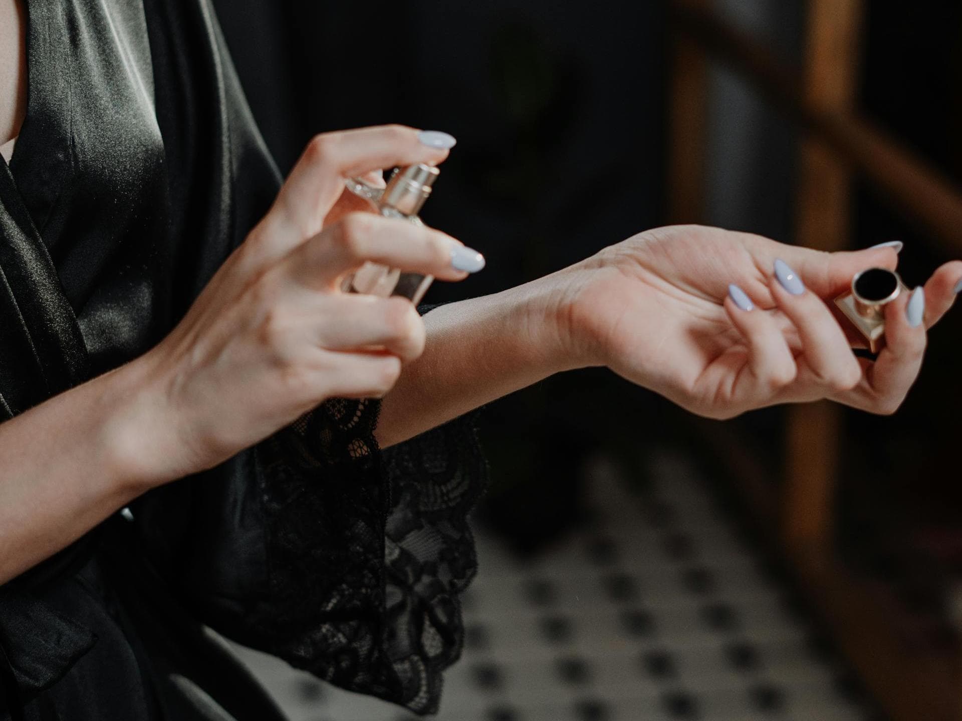 Arabische Parfums haben eine besondere Wirkung. Frau sprüht sich ein Parfum auf das Handgelenk und trägt ein schwarzes Nachthemd.