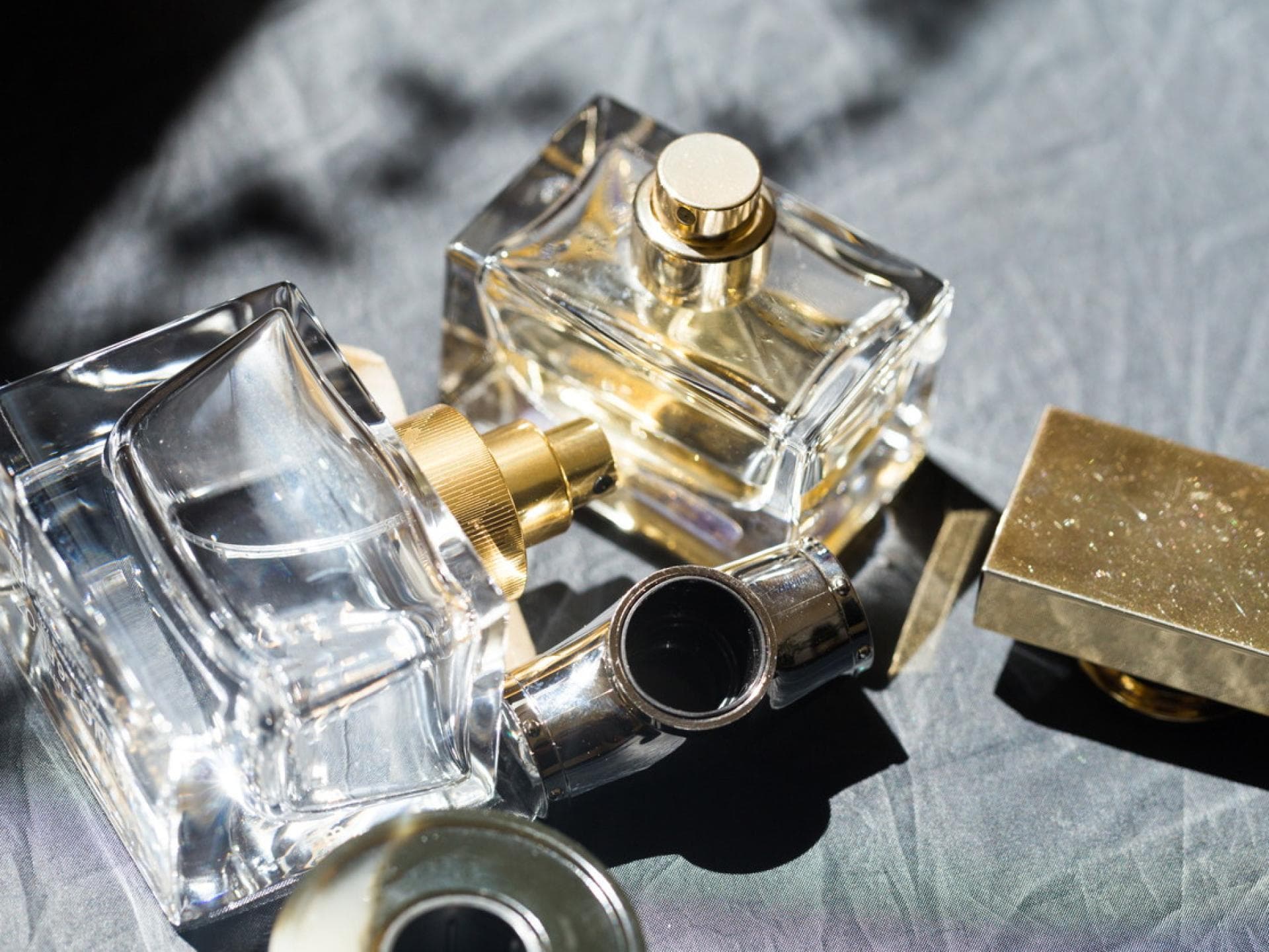 Pheromon Parfums haben eine besondere Anziehungskraft. Parfum Flakons liegen auf einem grauen Hintergrund.