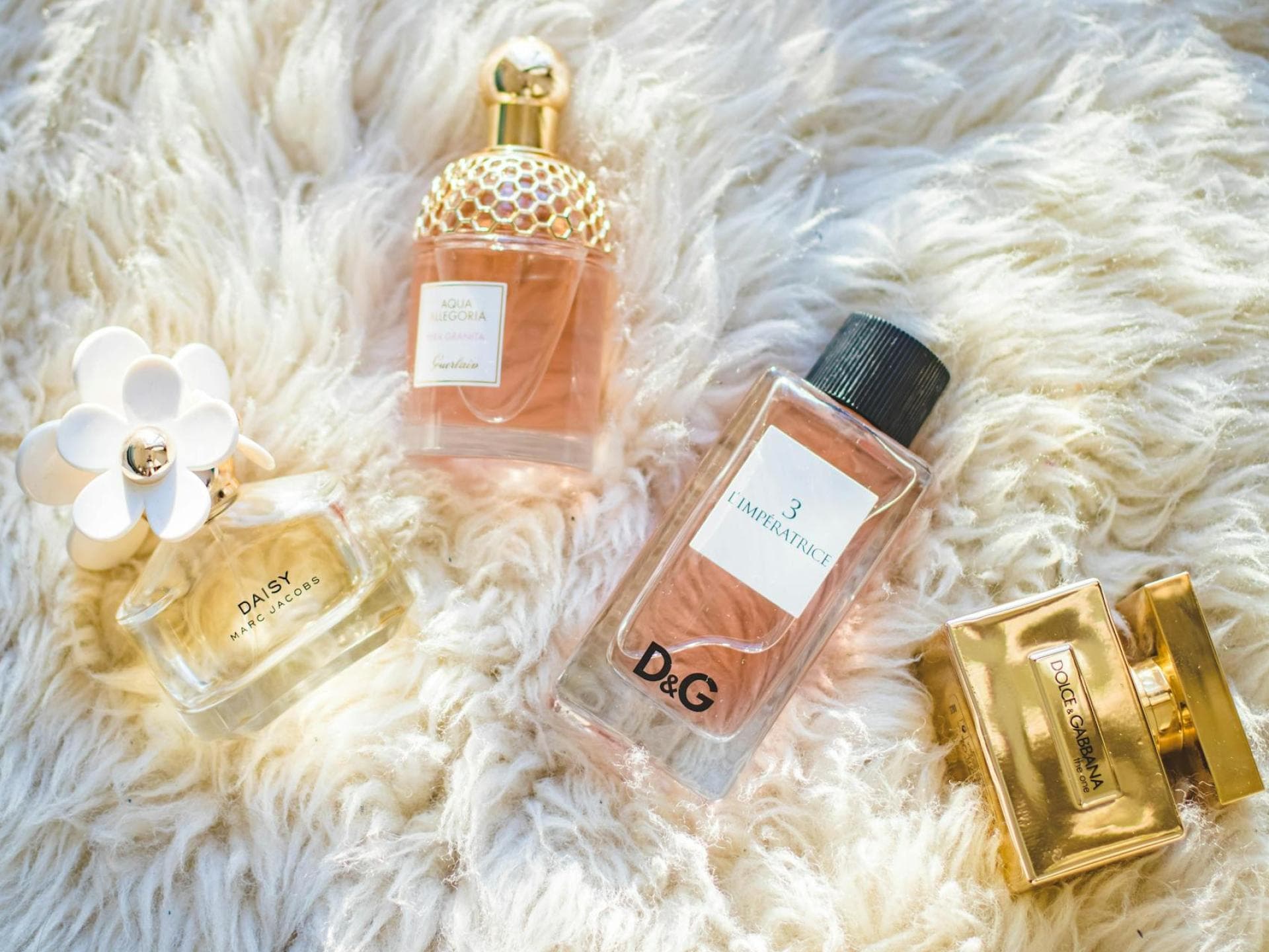 Gourmand-Düfte sind 2025 besonders beliebt. Verschiedene Parfums auf einem flauschigen weißen Teppich.