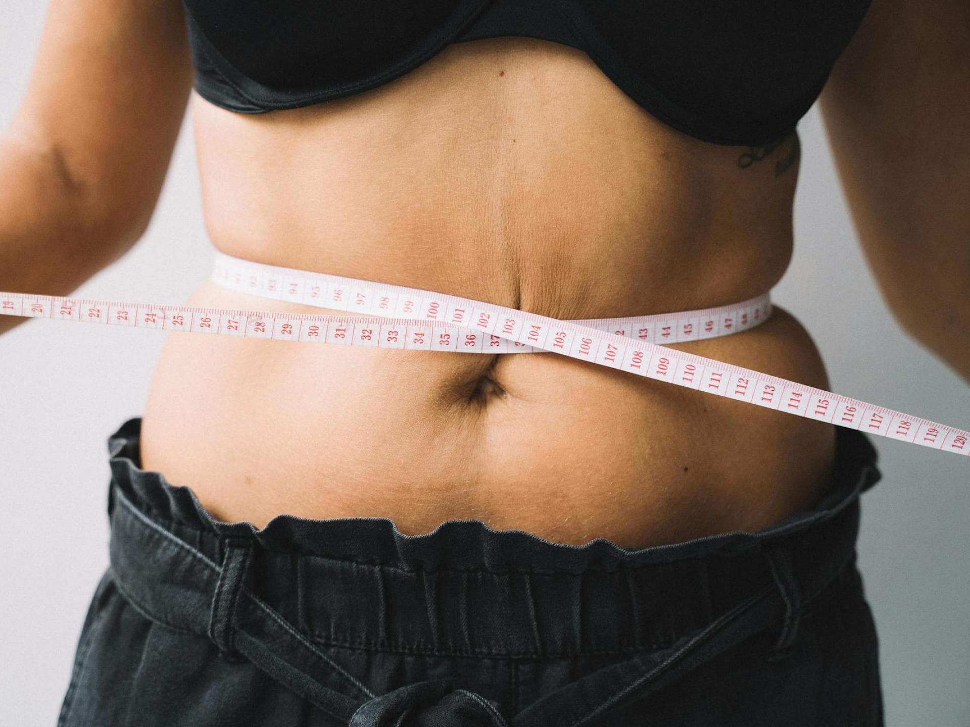 Der Body Round Index gibt Aufschluss über den Taillenumfang. Maßband um den Bauch einer Frau