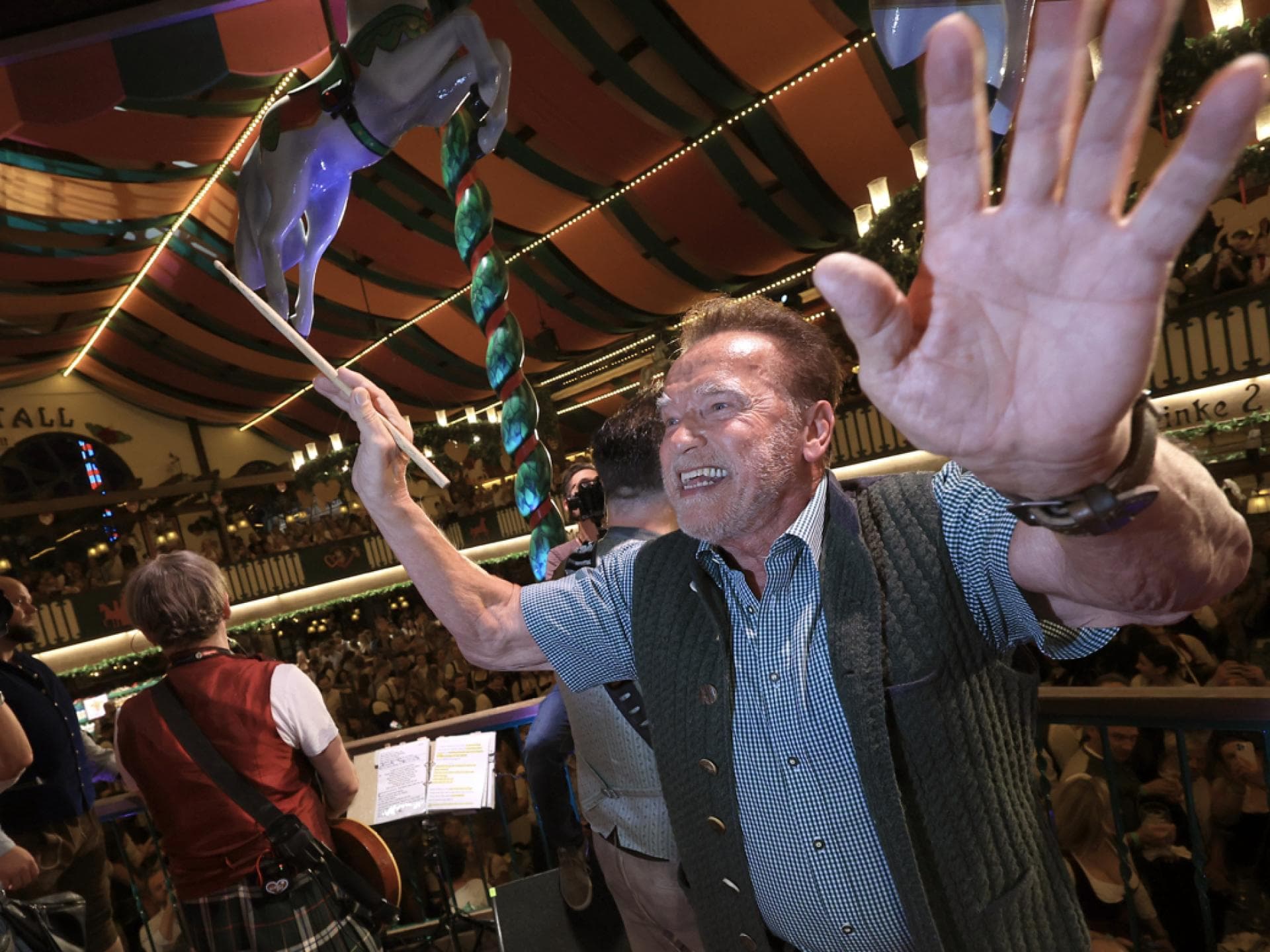 Arnold Schwarzenegger dirigiert im Marstall-Zelt die Kapelle auf der Wiesn