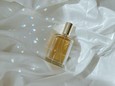 Parfum Flakon liegt auf einem Bettlaken mit Licht und Schatten