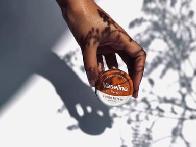 Frau hält eine kleine Dose mit Vaseline in der Hand.