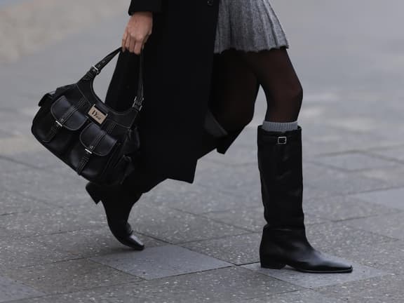 Frau trägt Stiefel und Dior-Tasche Frau trägt Stiefel und Dior-Tasche